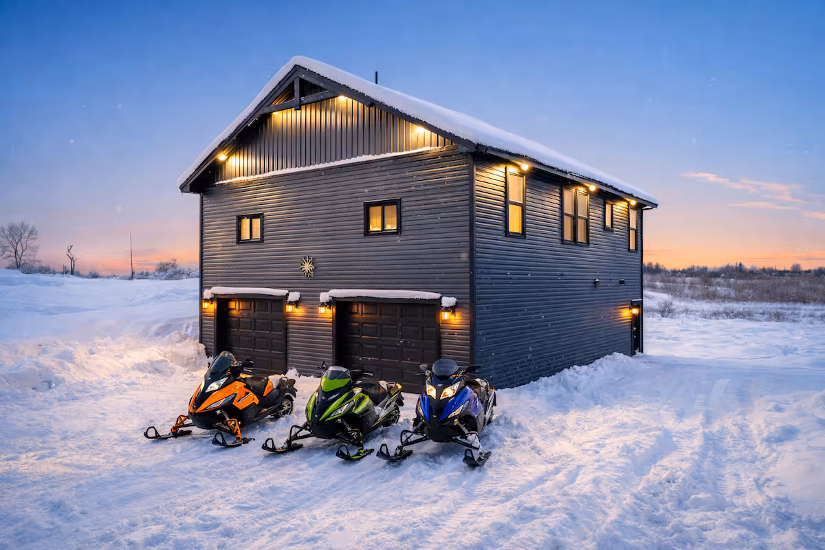 Exterior of Cozy Trailside Lodge 1 at dusk with snow on the ground and three snowmobiles parked out front