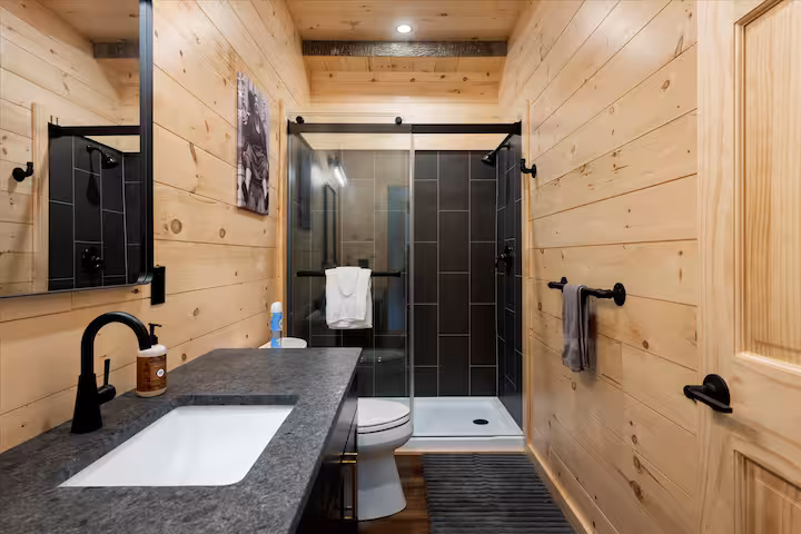 Modern bathroom with a black-tiled glass shower and dark countertop
