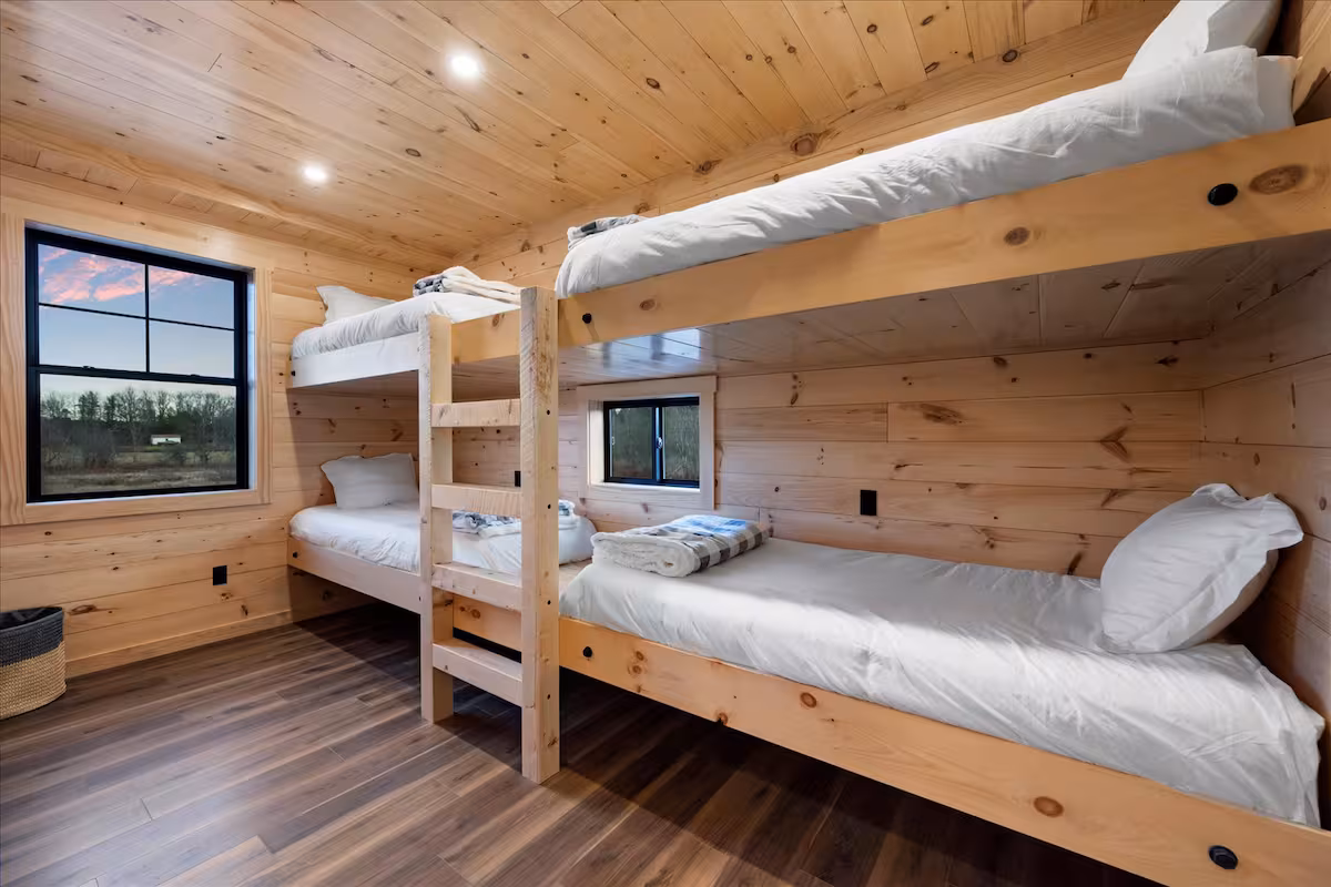 Built-in pine bunk room with two sets of twin bunk beds and a sunset view out the window