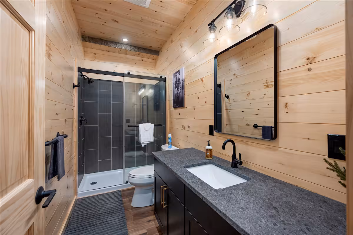 Modern bathroom with a black-tiled glass shower and dark stone countertop