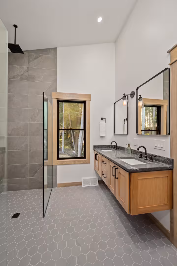 Modern bathroom with a walk-in rain shower, gray hexagon tile floor, and a double vanity