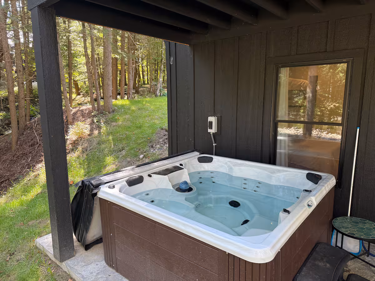 Private hot tub tucked under the deck in the woods beside the house